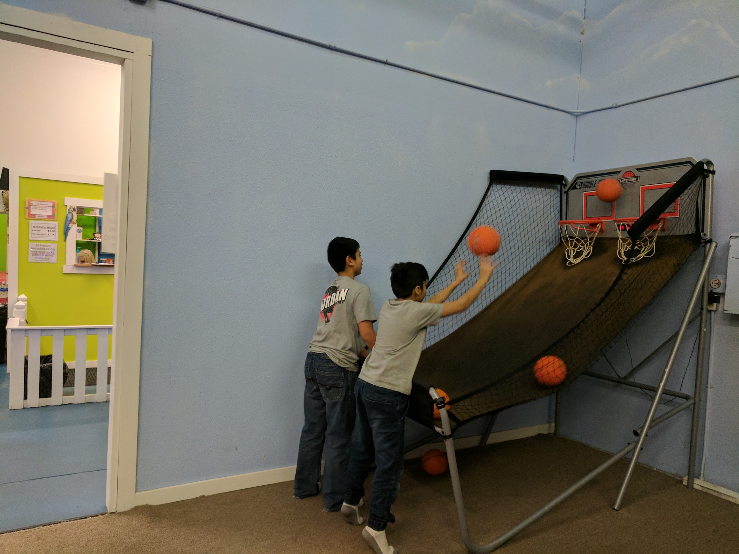 Two boys playing a basketball arcade game in the arcade corner at Inflatable Fun Gym