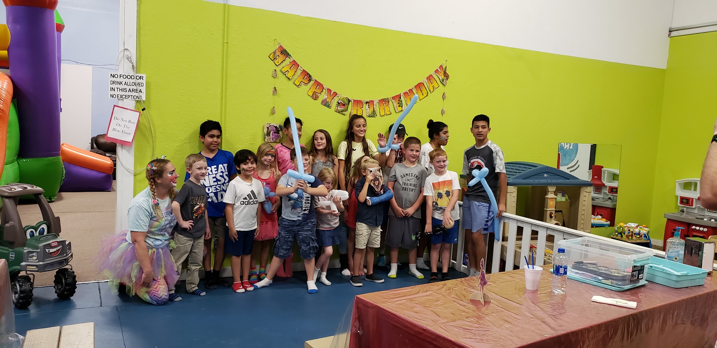 A real birthday party at Inflatable Fun Gym, with kids holding balloon swords in front of a Happy Birthday banner