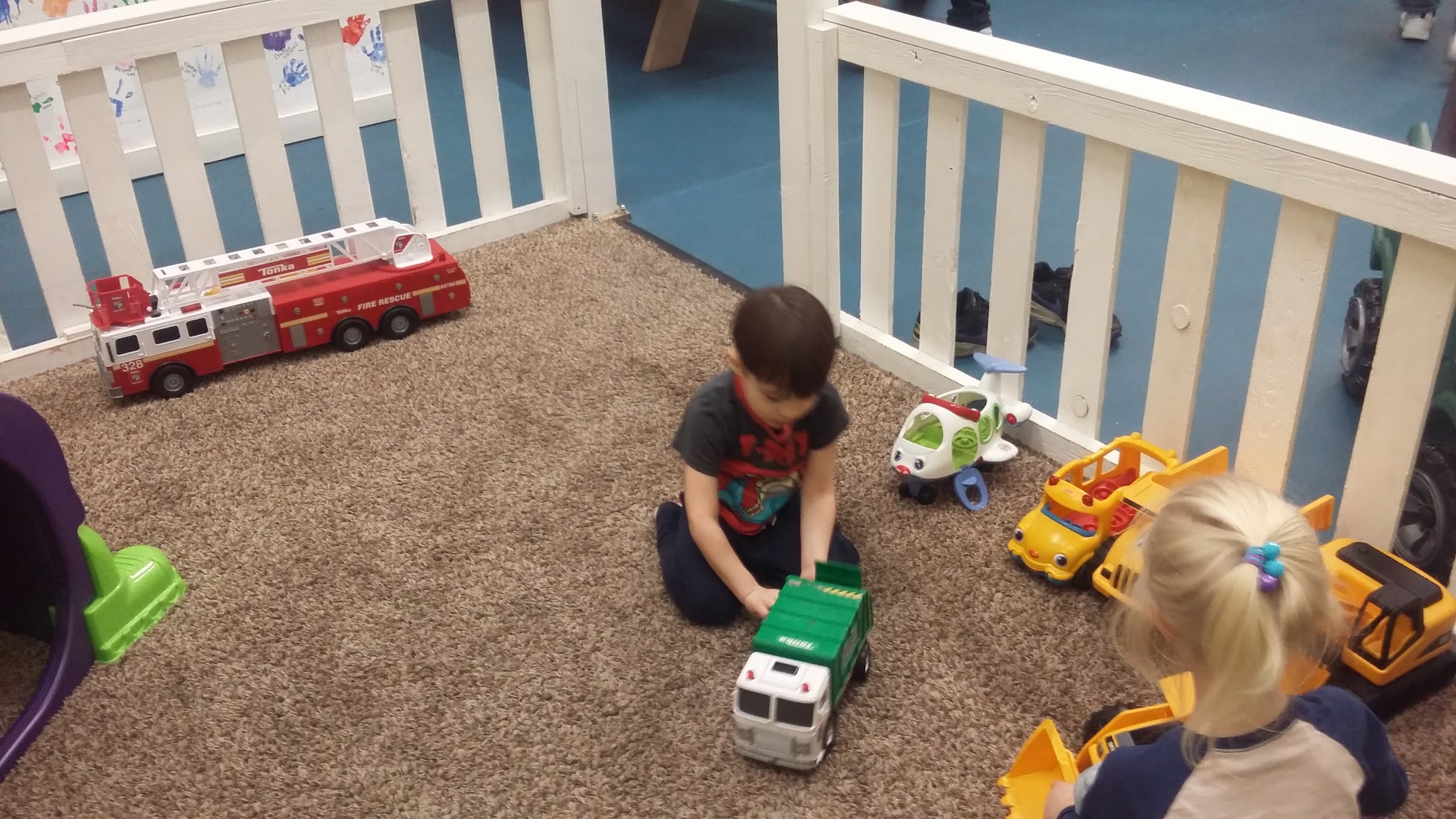 A young boy and girl playing with toy trucks in the toddler corner at Inflatable Fun Gym
